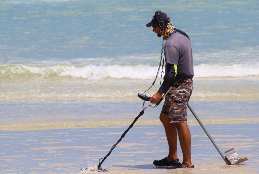 man using metal detector in a beach